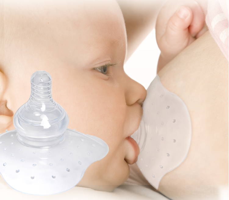 A baby sucks from a woman's breast through a nipple shield